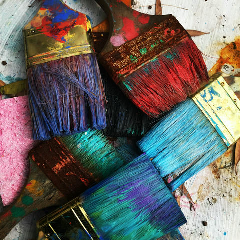 An assortment of wildy coloured square painbrushes stained with paint